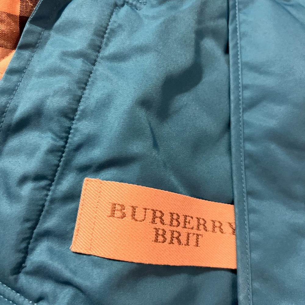 Quilted button front jacket with the brand's signature check print at interior.